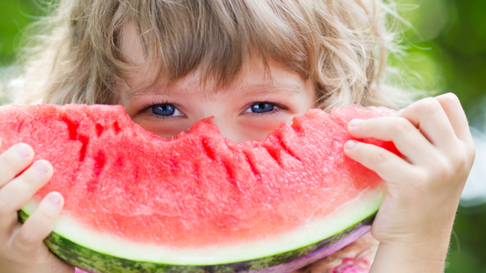 Smiling girl eating watermelon—capturing how simple pleasures help wire the brain for happiness and emotional well-being.