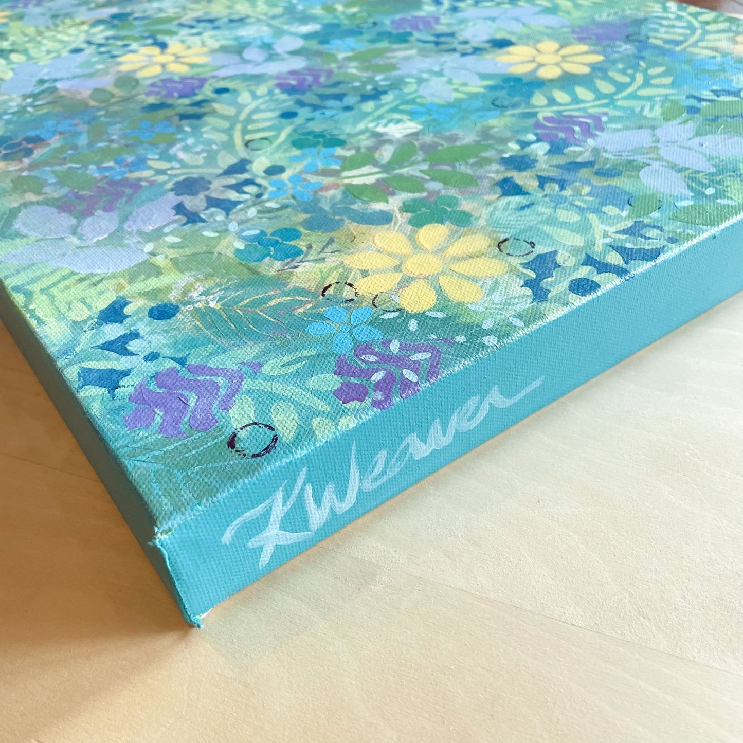 side of abstract floral painting on canvas sunny yellow flowers and small blue flowers green leaves purple accents refreshing jungle feel