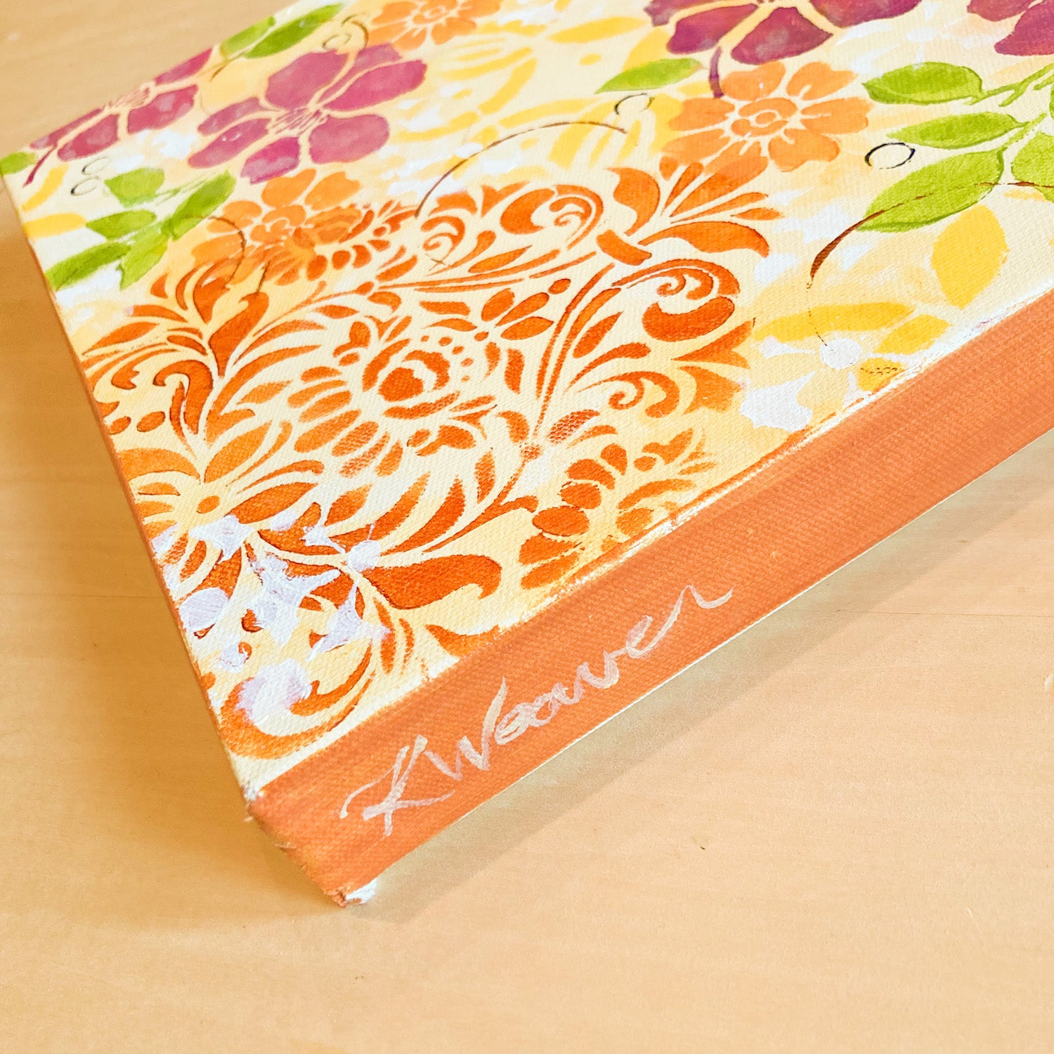 side view floral Hawaiian theme acrylic painting on canvas dark pink flowers orange flowers green leaves circles and scrolling shapes warm and cheerful sides painted orange