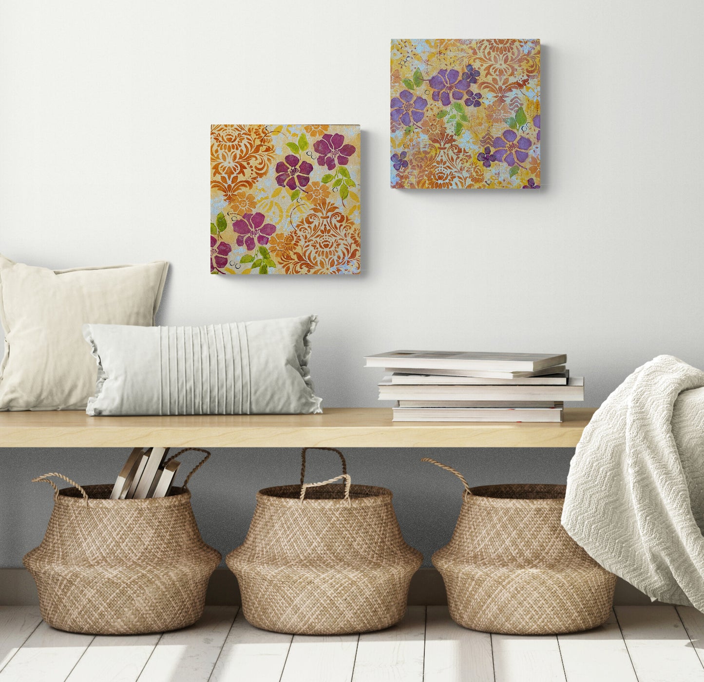 two floral Hawaiian theme acrylic paintings on canvas dark pink flowers orange flowers green leaves circles and scrolling shapes warm and cheerful shown in room with bench and baskets below