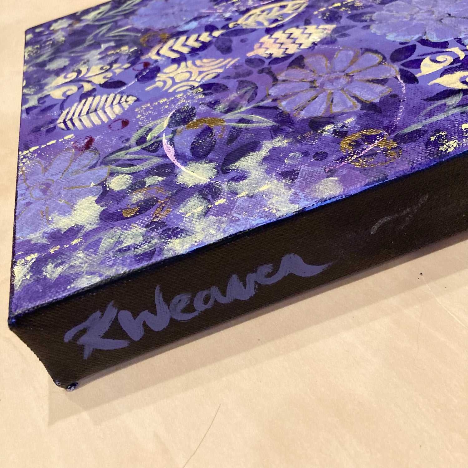 side photo of original abstract acrylic floral painting purple flowers and green leaves on purple background cream leaf shapes mysterious and vibrant