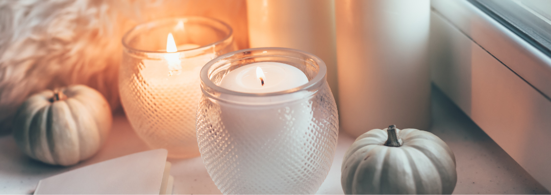 candles by a window with small green pumpkins decorating the space