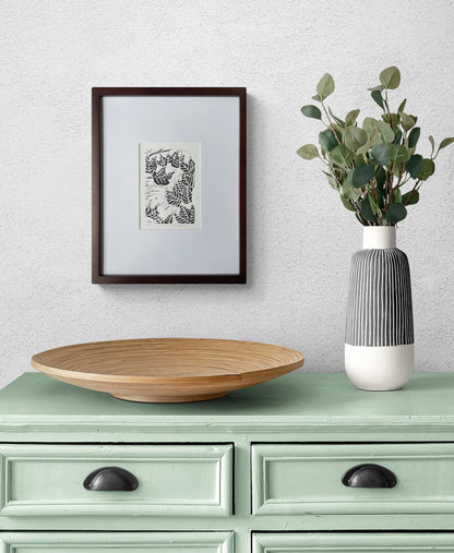 Fall leaf linocut print by Katie Weaver in black ink displayed above a dining room hutch with simple decor
