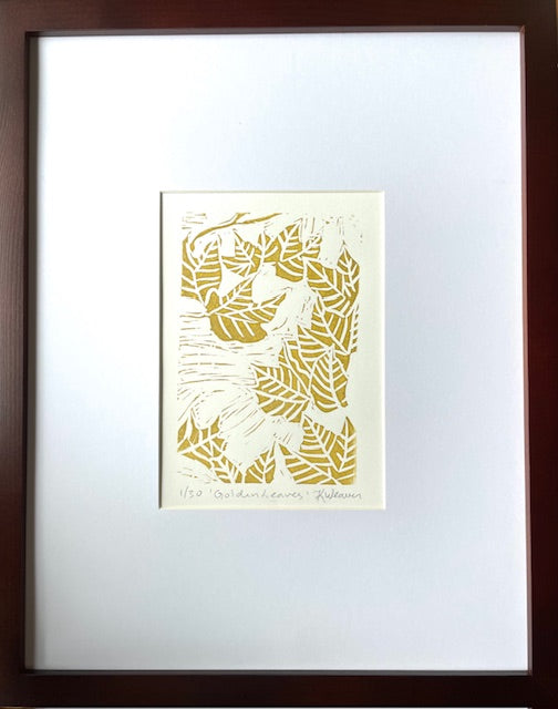 Fall leaf linocut print by Katie Weaver with winding gold leaf motifs shown in a mat and frame