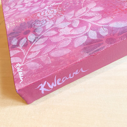 side view of original abstract painting with warm pink background white roses and leaf prints dark flowers layered underneath emits warm feeling of love
