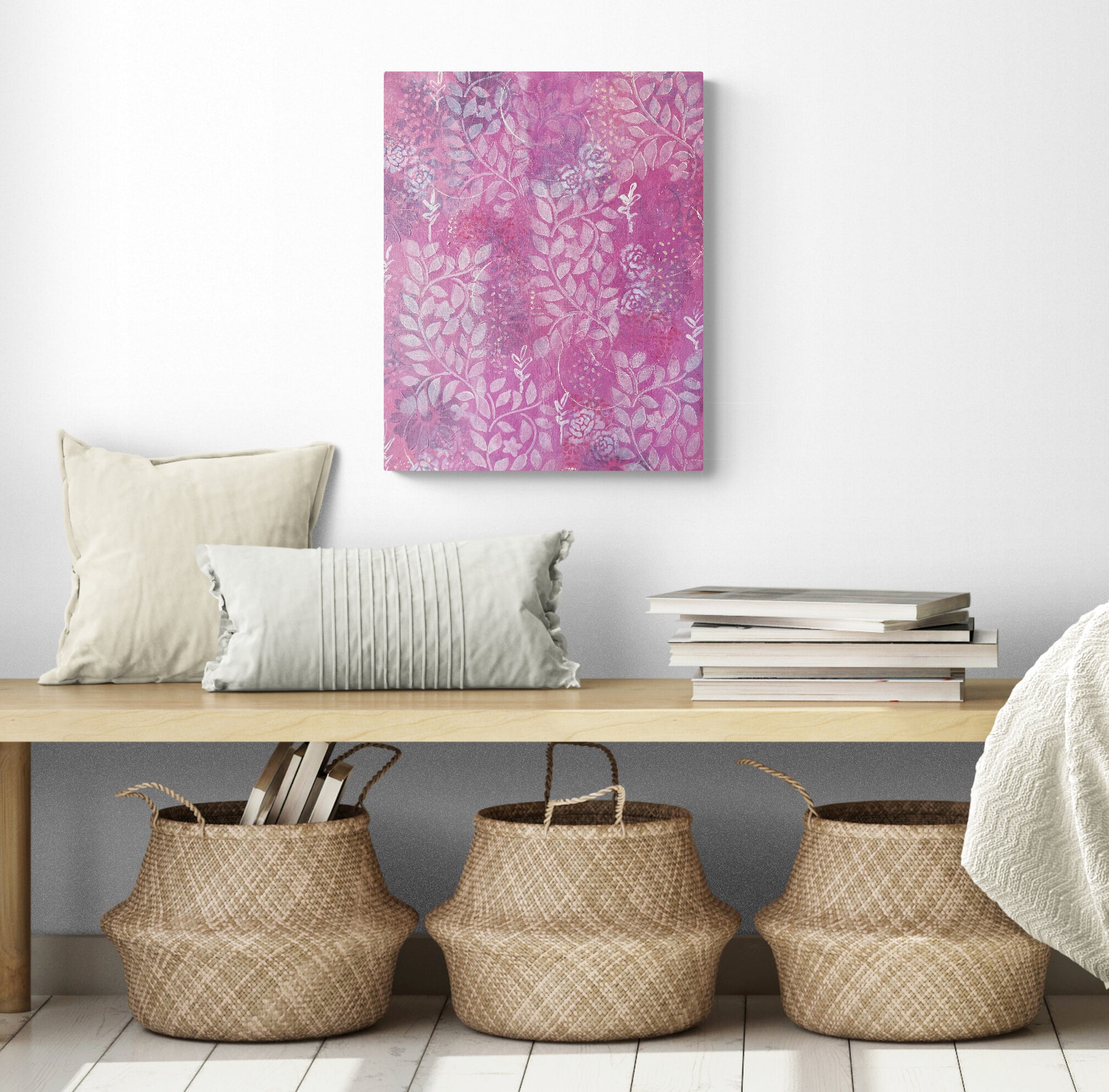 original abstract painting on canvas with warm pink background white roses and leaf prints dark flowers layered underneath emits warm feeling of love shown in room with bench and baskets below