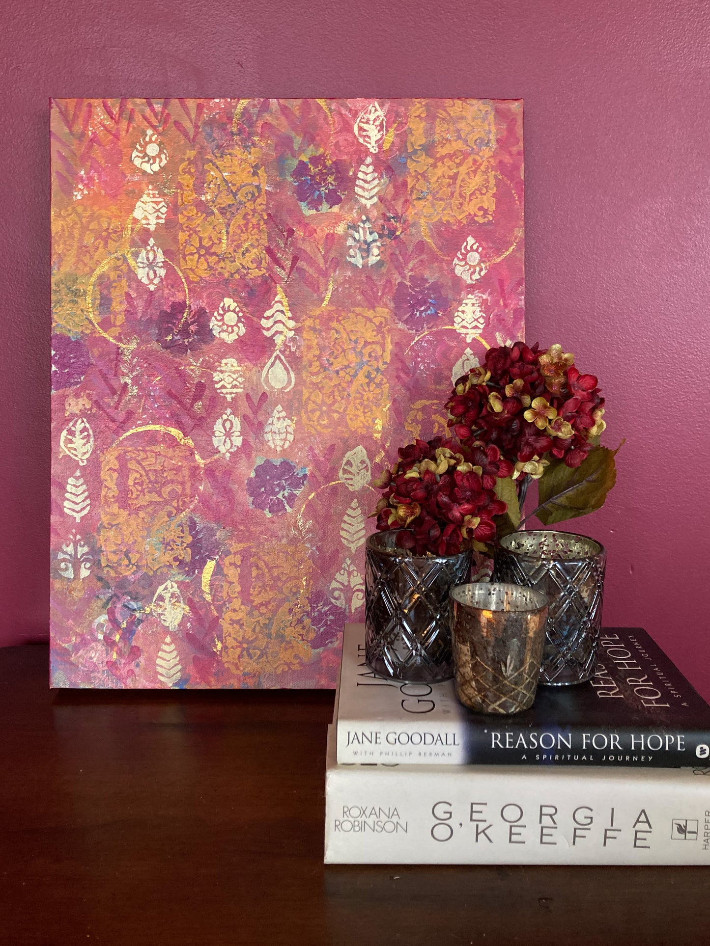 photo of red and orange abstract acrylic painting in room with red flowers candles and books