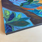 Side view of bright abstract acrylic painting of purple tulips green and blue leaves and orange background